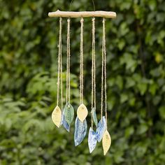 a wind chime hanging from a tree branch in front of some green leaves and trees