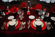 the table is set with red roses and silverware