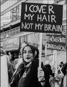 a woman holding a sign that says i love my hair not my brain, with other people in the background