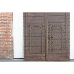 an old pair of wooden doors in front of a brick wall