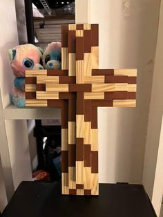 a wooden cross sitting on top of a table next to a stuffed animal and other items