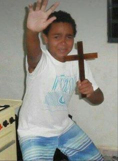 a young boy is holding up a cross