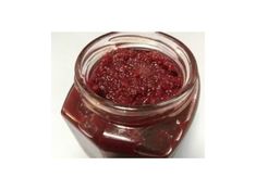 a jar filled with raspberry jam sitting on top of a table