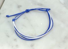 Simple, yet stylish this waxed cord bracelet is 100% waterproof you can shower and swim with it on without taking it off. It is adjustable and fits size 6-11" wrists.  Style Includes: * Blue and White  * Adjustable 6-11" * Handmade in Minnesota   DESIGN YOUR OWN BRACELET: * If you'd like different colors in your bracelet select 'Custom' from the drop-down menu. * In the note to seller box note what colors you'd like  Material: * Polyester Waxed Cord  Bracelets Perfect for: * Everyday Wear * Women, Men and Children * Cancer Awareness * Fundraisers * Ride/Run for a cause     Check out other colors here: https://www.etsy.com/shop/FlyingBirdJewelry?ref=hdr_shop_menu&section_id=21527702 INTERNATIONAL ORDERS: * International orders are taking over a month and a half to arrive at its destination. Friendship Bracelet String, Wax Cord Bracelet, Bracelet String, Bracelet Cord, Handmade Friendship Bracelets, Bracelet Friendship, White Wax, Cord Bracelet, Copper Bracelet