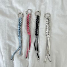 four different colored lanyards are on a white sheet, one has a keychain and the other has a chain attached to it