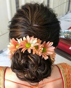 a woman with flowers in her hair is looking down at the ground while wearing an orange dress