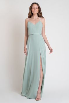 a woman in a long green dress with a slit down the side and one leg