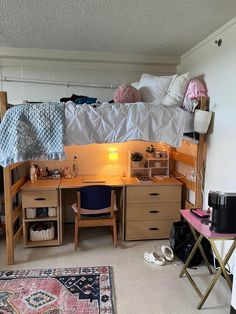 a dorm room with a desk, bed and rugs on the floor in front of it