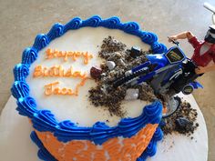 a birthday cake with an image of a motorcycle and rider on the top is blue and orange frosting