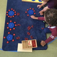 two children playing with numbers and shapes on the floor in front of a blue rug