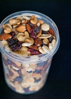 a plastic cup filled with nuts and raisins on top of a black table