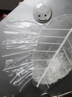 a metal object with plastic wrap around it and a smiley face drawn on the side