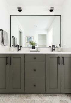 a bathroom with two sinks and a large mirror on the wall above it's cabinets