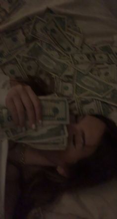 a woman laying in bed covered with money