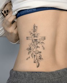 a woman with a cross tattoo on her lower back is holding onto the side of her stomach