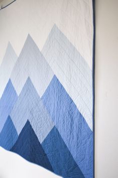 a blue and white quilt hanging on the wall