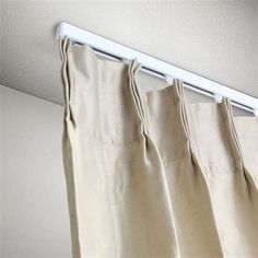 curtains hanging on a rod in front of a white wall with a light coming from it