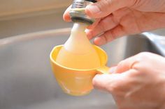 a person is pouring something into a yellow cup with a metal faucet in it