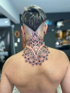 the back of a man's neck with an intricate tattoo design on his neck