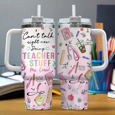 two travel mugs sitting on top of a desk