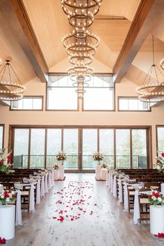 the inside of a wedding venue with white and red flowers on the floor, chandeliers hanging from the ceiling