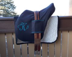 a horse saddle with the monogrammed k on it's side hanging from a fence