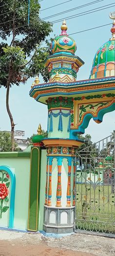 a colorfully painted building with an iron fence around it and trees in the background