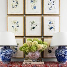 two blue and white vases sitting on top of a table with flowers in them