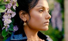 a close up of a person with flowers in her hair and wearing earrings on their head