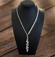 This lariat-style necklace combines the timeless elegance of pearls with the sleekness of sterling silver chain. It features a descending line of lustrous pearls that dangles gracefully from a silver curve, offering a sophisticated and modern twist on classic pearl jewelry. Perfect for both day and evening wear, it adds a refined touch to any ensemble. Silver Lariat Backdrop Necklace With Pearl Drop, Silver Lariat Necklace With Pearl Drop, Silver Lariat Backdrop Necklace With Pearl Chain, Silver Lariat Pearl Necklace With Adjustable Chain, White Pearl Chain Lariat Necklace, Silver Lariat Necklace With Pearl Chain, Silver Backdrop Necklace With Pearl Chain For Gift, Silver Pearl Lariat Long Necklace, Silver Lariat Necklace With Pearl Pendant