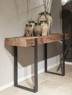 a wooden table with vases on it and a tripod light in the background