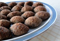 a white plate topped with lots of chocolate covered doughnuts on top of a table