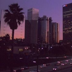 the city skyline is lit up at night, with many cars driving on the road