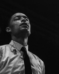 a black and white photo of a man with his eyes closed wearing a neck tie