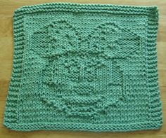 a crocheted dishcloth is sitting on a wooden table with a green square in the middle