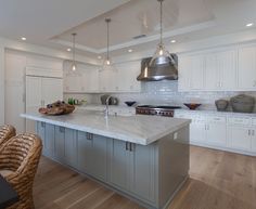 a kitchen with white cabinets and an island in the middle is lit by pendant lights