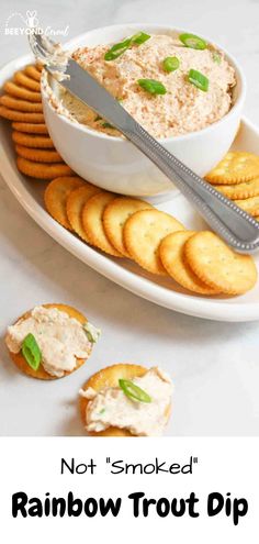 a white plate topped with crackers and a bowl filled with dip surrounded by crackers