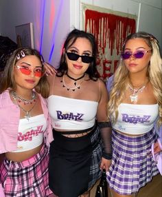 three girls in matching outfits posing for the camera with one girl wearing sunglasses on her head