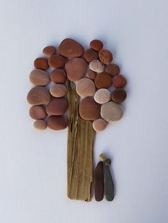 a tree made out of rocks sitting on top of a piece of wood next to a rock