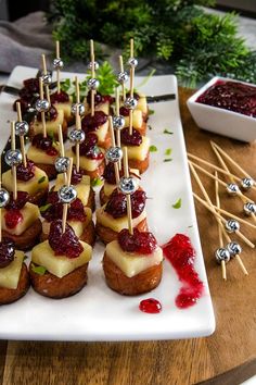 small appetizers are arranged on a plate with toothpicks and cranberry sauce