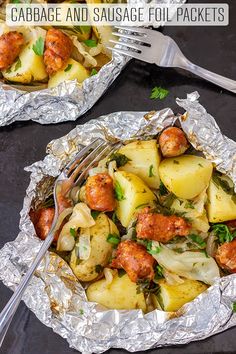 two foil packets filled with sausage and potatoes on top of a black surface next to a fork