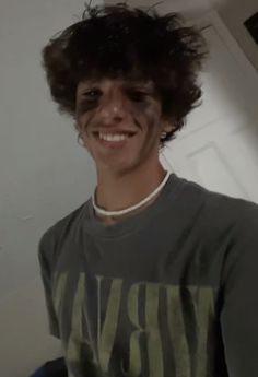 a young man with curly hair smiling at the camera