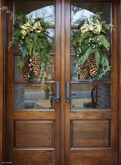 two wooden doors with wreaths and pine cones on them