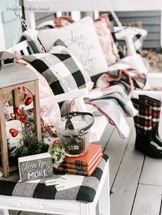 the porch is decorated for christmas with plaid pillows and other holiday decorations on it's bench