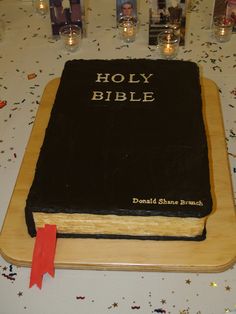 a large bible cake on a table with candles and confetti all around it