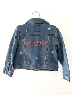 A custom baby name denim jacket is an adorable addition to your child's wardrobe, a great way to announce your baby's name to the world, and would make an amazing baby shower present or child's birthday gift. Allow your son or daughter to celebrate their name through flaunting it on their attire. When your little guy or gal grows out of their jean jacket, it will be a special keepsake to cherish for years to come.  All custom pieces are hand-embroidered with the name of your choice after your purchase is made.  To complete your order, please leave your baby's name and your string color in the personalization box (any string color not specified will be stitched in white) and select your coat size and color from the drop-down menu. If you order the design with flowers, flowers will be white Jacket Craft, Custom Jean, Jean Jacket Patches, Custom Jean Jacket, Embroidered Jean Jacket, Kids Jackets, Baby Jeans, Custom Jeans, Baby Shower Presents