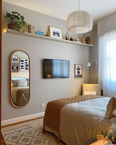 a bed room with a neatly made bed and a large mirror on the wall above it