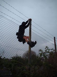 a person climbing up the side of a fence