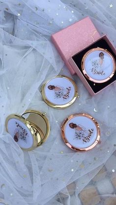 three pieces of jewelry sitting on top of a white cloth covered table next to a pink box