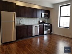 an empty kitchen with wood floors and white appliances